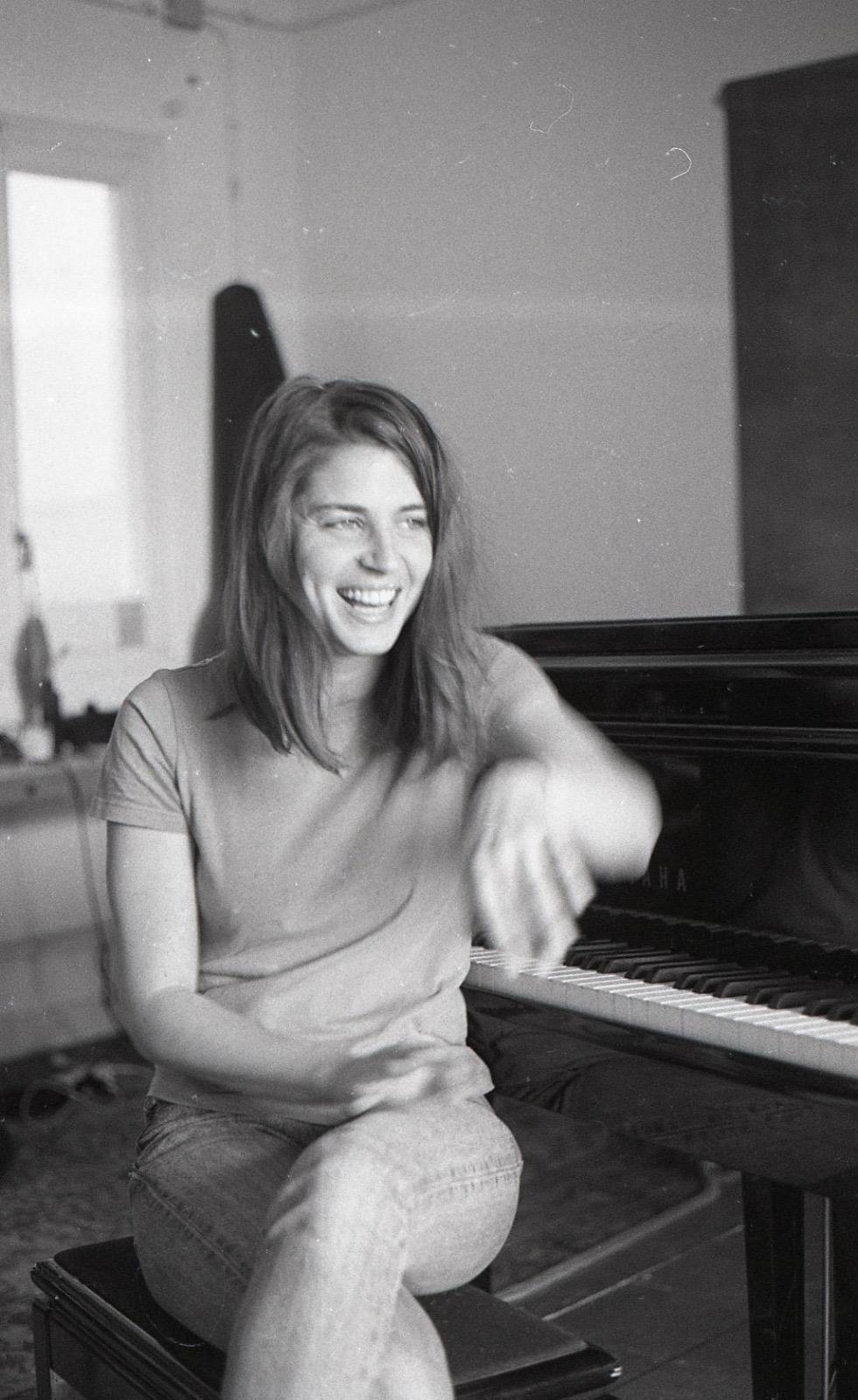 Retrato en blanco y negro junto al piano que transmite la cercanía, creatividad y personalidad artística de Lucía Fumero.